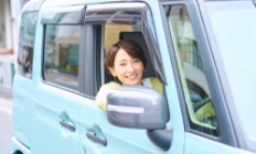 自動車の運転席から女性が顔をだしている写真